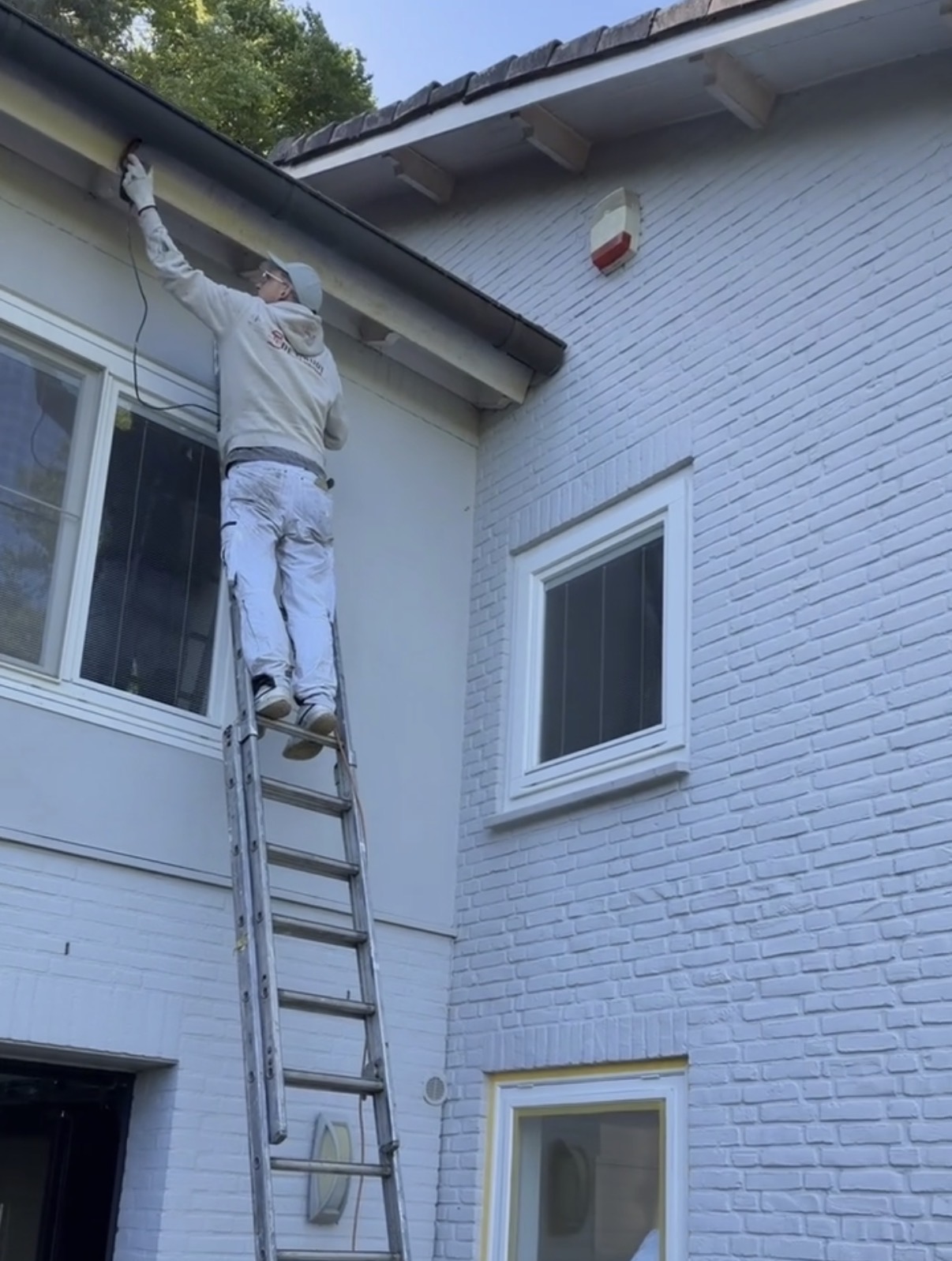 Schilder aan het werk aan gevel en dakrand