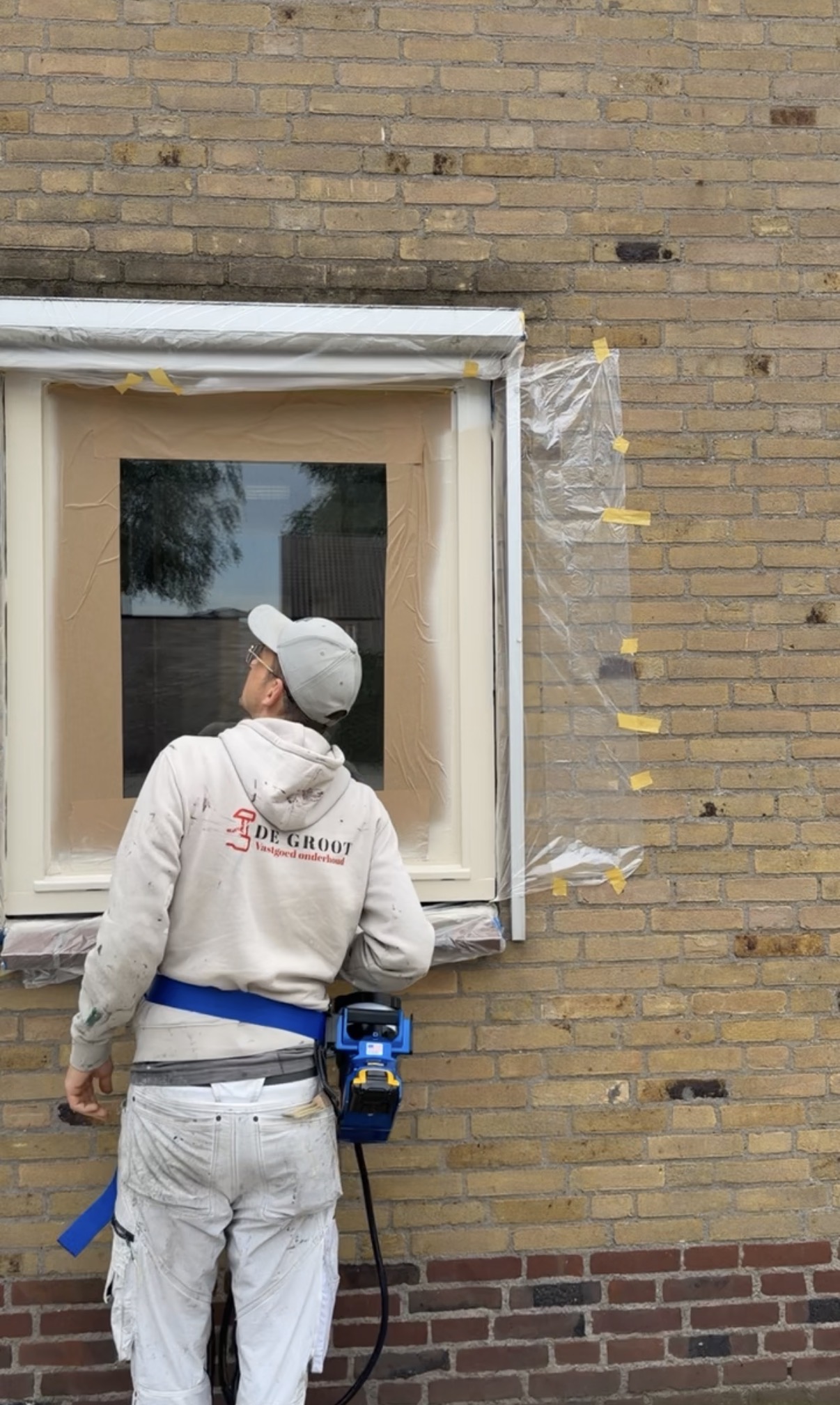 Vakman werkt zorgvuldig aan een afgeplakt kozijn